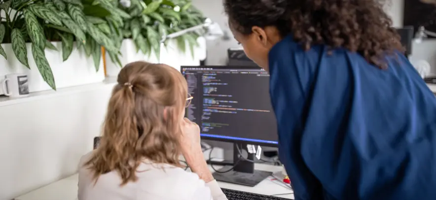Women looking at code on a monitor