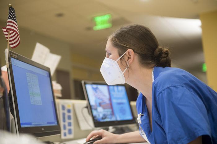 hospital worker examining workstation screen hospital worker examining workstation screen