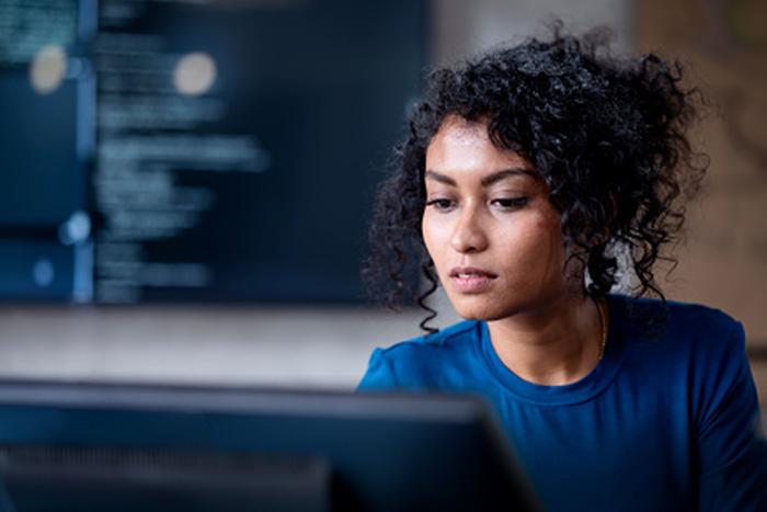 Reduce your IT anxiety Woman working on a computer with cybersecurity code in the background
