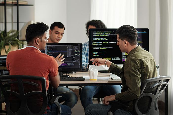 5 Digital Experience Monitoring Predictions for 2025 Workers discuss the contents of a computer screen