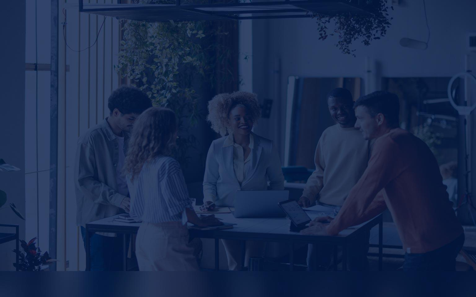 A team of individuals engaged in discussion around a table with laptops, showcasing Zscaler's commitment to collaboration and progress.