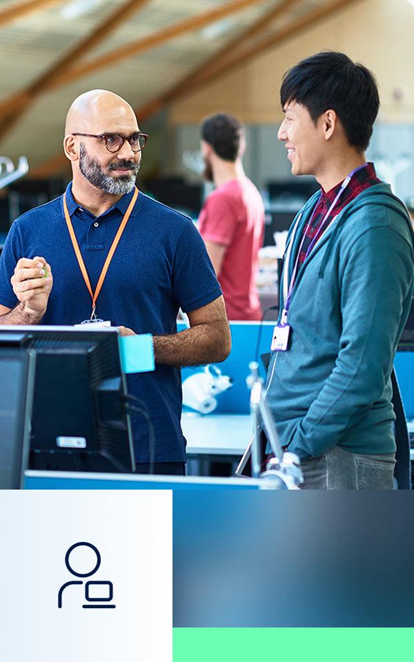 Two individuals conversing in front of a computer screen at a Zscaler Cyber Academy live training event.