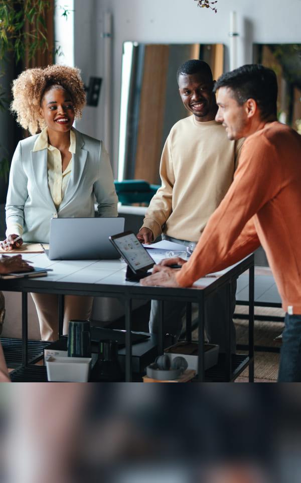 A team of individuals engaged in discussion around a table with laptops, showcasing Zscaler's commitment to collaboration and progress.