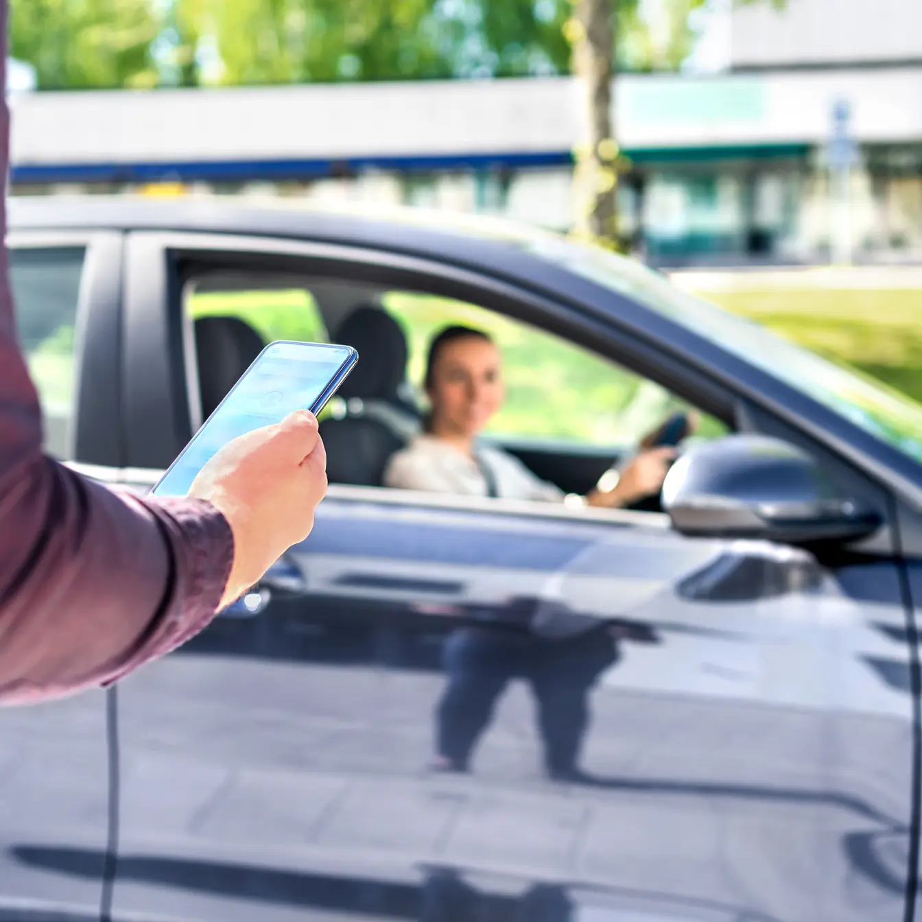 Man with phone in hand with woman driving a car in the background